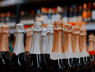 Row of shining bottle necks covered with foil. Holiday atmosphere. Close-up in a shop. Champagne...