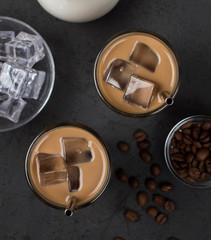 Coffee milk with ice in a glass with a metal tube on a dark gray background top view