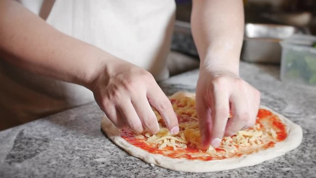 Italian chef prepares real Italian pizza, sprinkles pizza with parmesan cheese.