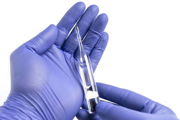 Hand in blue glove holding a glass ampoule with the vaccine or medicine. White background. Medical mocku up.