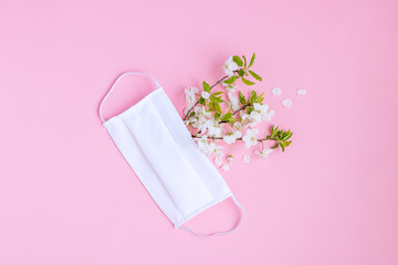 Abstract composition of a handmade protective mask and flowering branches. Concept of prevention and fight against a new coronavirus COVID-19. Spring and hope.