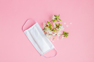 Abstract composition of a handmade protective mask and flowering branches. Concept of prevention and fight against a new coronavirus COVID-19. Spring and hope.