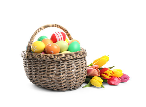 Bright Easter eggs in wicker basket and tulips isolated on white background