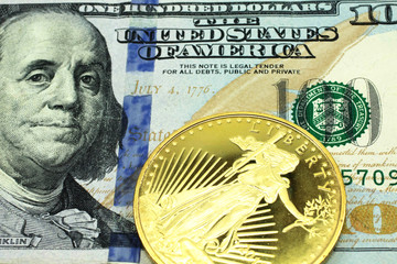 A macro image of a blue American one hundred dollar bill with a gold coin.  Shot close up.