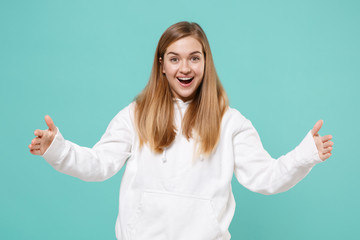 Surprised young woman girl in casual white hoodie posing isolated on blue turquoise background. People lifestyle concept. Mock up copy space. Gesturing demonstrating size with horizontal workspace.