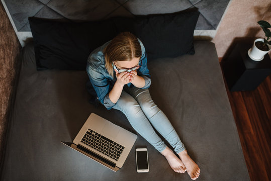 Coronavirus. Cough. Business woman working in home wearing protective mask in quarantine. Stay at home. Girl learns, using laptop computer in bedroom. Freelancer. Communication and technology concept.