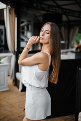 Fototapeta premium A beautiful young girl is standing on the veranda of a beautiful house.