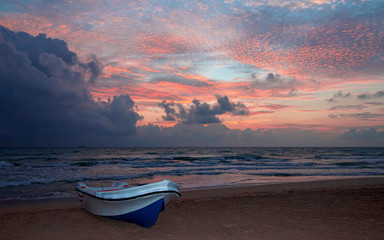 Colorful ocean beach sunrise with boat on foreground. beautiful cloudscape.