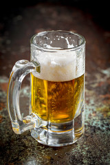 Light frothing beer in a glass, on an old background.