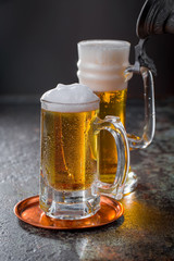Light frothing beer in a glass, on an old background.