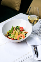 Salad with shrimp, cucumber, olives, tomatoes and basil. Glass of white wine. Place for text