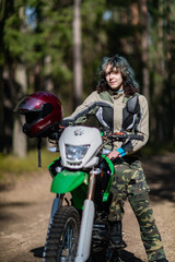 Fototapeta na wymiar beautiful girl posing on a motorcycle, curly hair, young girl, biker, equipment for a motorcyclist, beautiful poses, attracts, motorcycle driver, concept, active lifestyle, enduro