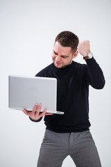 A male businessman manager smiles and stands with a laptop in his hands and looks at the screen. Stands on a white background.