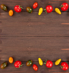 Top view of frame from fresh vegetables, colorful cherry tomatoes and mini peppers on rustic wooden background with copy space