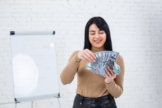 Photo of a charming woman with a smile holding a fan of money in her hands