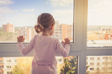 Little girl looking outside through the window