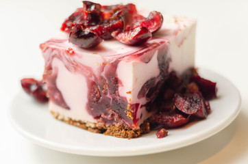 Japanese cheesecake with cherry sauce and fresh cherries on the ceramic plate and red background