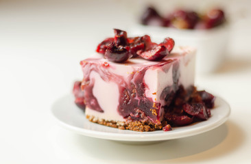 Japanese cheesecake with cherry sauce and fresh cherries on the ceramic plate and red background