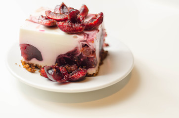 Japanese cheesecake with cherry sauce and fresh cherries on the ceramic plate and red background