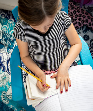 Young child doing reading and writing in her tree house fort while school is closed