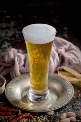 Light frothing beer in a glass, on an old background.