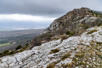 The mountain over grotto of Mary Magdalene at cloudy weather, clouds over a valley, a dry grass