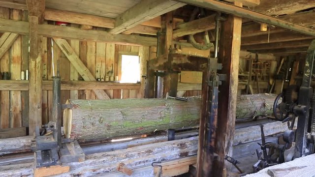 In einem alten wasserbetriebenen S&auml;gewerk wird ein Baumstamm zu Brettern ges&auml;gt