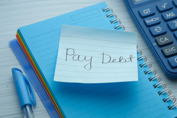 pay debt word on notepad with calculator, close up
