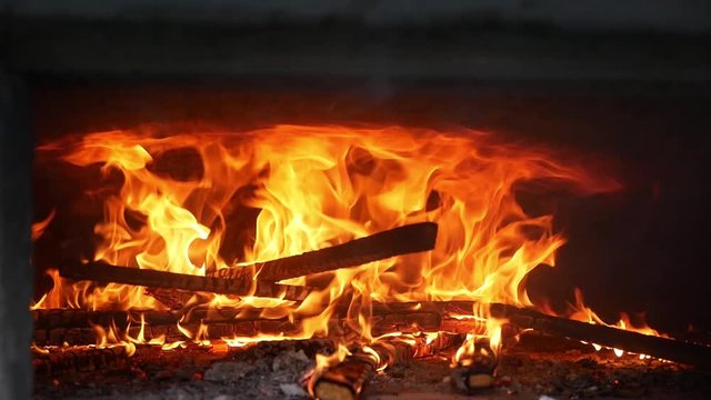 Loderndes Feuer mit Holzscheiten in einem alten Brotbackofen