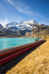 the fast Bernina Express train crosses the Bernina pass in the background the peaks of the Alps, Graubunden, Switzerland
