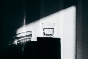 Fresh empty, drank glass of water on table in sun with shadow