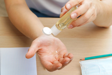 Young man applying sanitizer gel on his hands while sitting at his working table in office