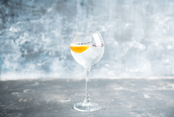 Gin based cocktail with lemon slice and juniper berries in wine glass. Selective focus. Shallow depth of field.