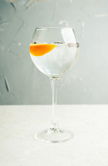 Gin based cocktail with lemon slice and juniper berries in wine glass. Selective focus. Shallow depth of field.