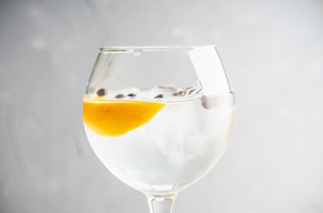 Gin based cocktail with lemon slice and juniper berries in wine glass. Selective focus. Shallow depth of field.