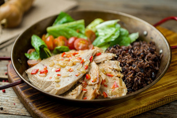 Turkey with black rice on old wooden table