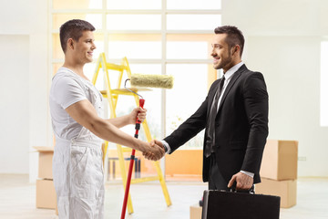 Decorator with a paint roller shaking hands with a businessman