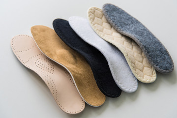 Studio photo of orthopedic insoles. A variety of orthopedic insoles are laid out in a row....