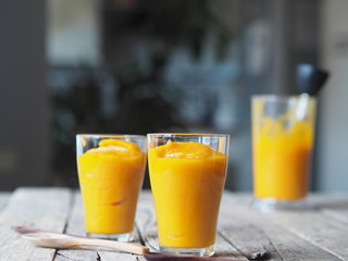 Natural smoothie in glasses made from the pulp of homemade pumpkin, on a wooden ancient background.Health benefits of pumpkin.