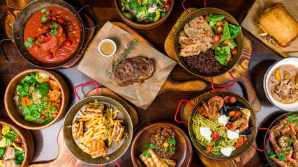 Assorted food set on table, Pasta with seafood, steak ribeye, club sandwich, turkey with black rice, salad with kinoa, tartar from beef, fried loungustine