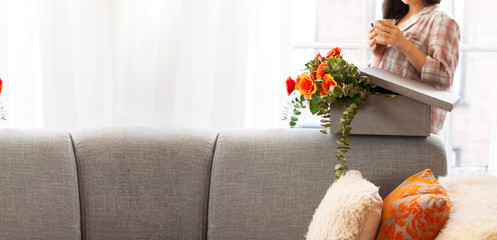 woman drinks coffee and enjoys the gift and flowers in the house by the window. Girl with a bouquet of roses. Concept of mother's day and womens day. Banner . Long format. Soft focus