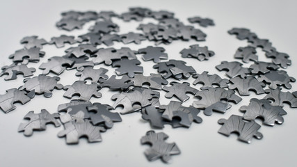 Metal jigsaw pieces on white background. Selective focus.