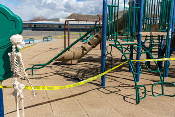 Adult skeleton leaning on playground equipment at an empty closed park on a nice day