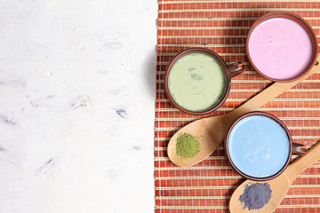 An assortment of colorful latte Japanese tea, golden turmeric, matcha, blue, pink moon milk. It has...
