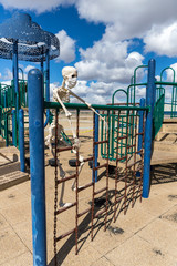 Skeleton climbing on ladder toy at an empty closed park on a nice day
