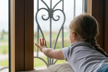 Stay at home quarantine coronavirus pandemic prevention, girl looking out of the window without being able to go out for a walk