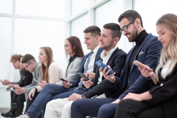 group of young business people with smartphones sitting in a row.