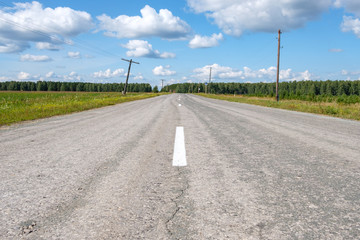 the road is paved and stretches away against the summer sky