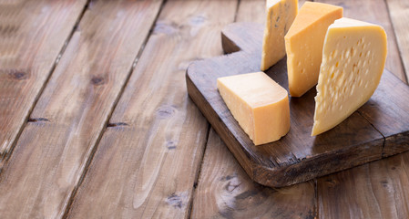 different cheese classic choice, on an old wooden board. Traditional Dutch cheese of different varieties. Free space for text. The concept of dairy products.