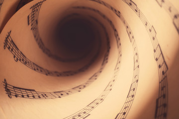 Rolled sheet with music notes as background, closeup